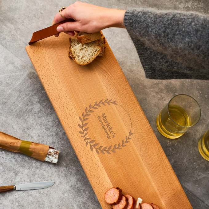 Hand pakt brood van een gegraveerde borrelplank